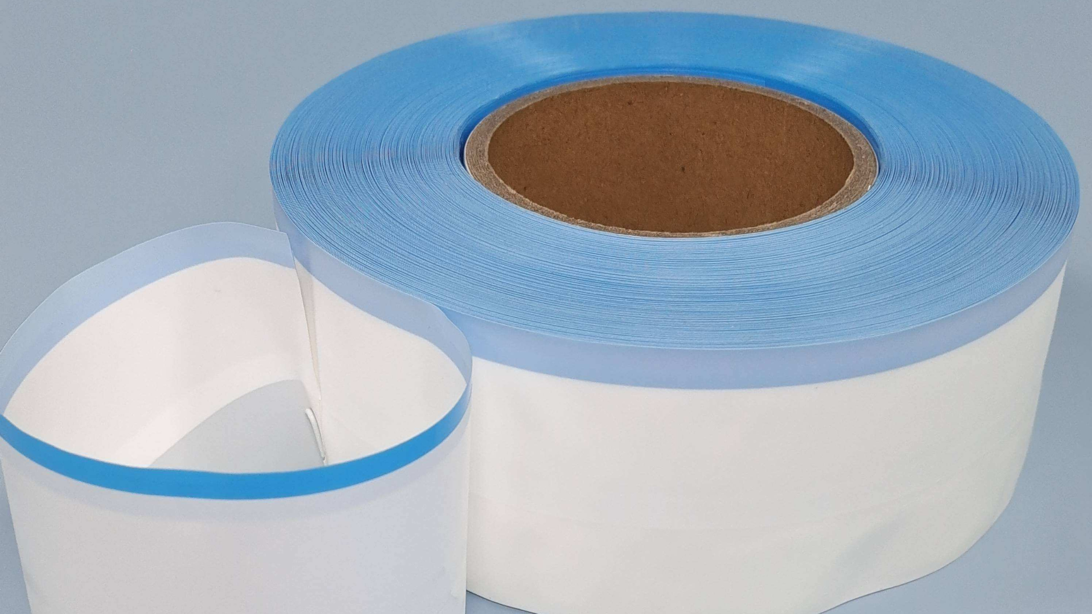 A photograph of a hand holding a roll of customized side tape for diaper with a brand logo printed on it, showing the customization options for manufacturers.