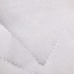 A large, pristine roll of soft disposable spunlace fabric ready for distribution, highlighting its quality and smooth texture.