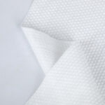 A large industrial roll of Polyester and Blended Spunlace Fabric, showcasing its pristine white color and smooth, uniform texture, manufactured by Favourite Fab.