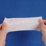 A professional holding the elastic non woven bandage roll, gently pulling to showcase its impressive stretch capacity.