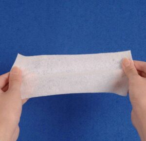 A professional holding the elastic non woven bandage roll, gently pulling to showcase its impressive stretch capacity.