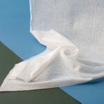 Hand holding a saturated sheet of Wet Wipe Embossed Spunbond demonstrating its superior strength and hydrophilic spunbond nonwoven properties.